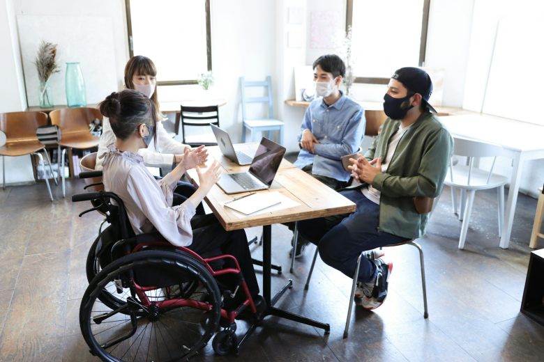 Woman on wheelchair with her colleague at office