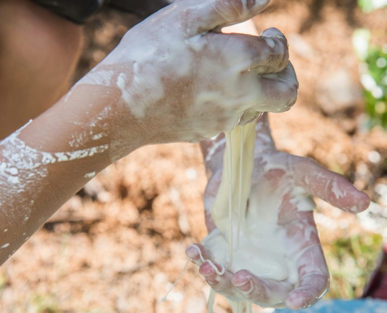 white goo stretches between two messy hands