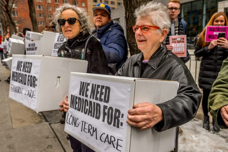 Women carry boxes labeled 'We need Medicaid for Long Term Care' and We need Medicaid for Pediatric Care' at a protest in 2017.
