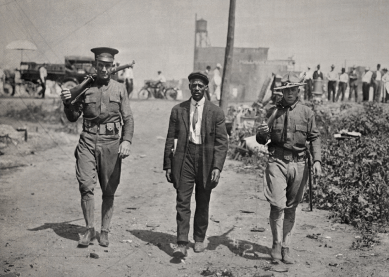 The winding path to economic freedom Two National Guardsmen escort a Black man after the East St. Louis massacre.